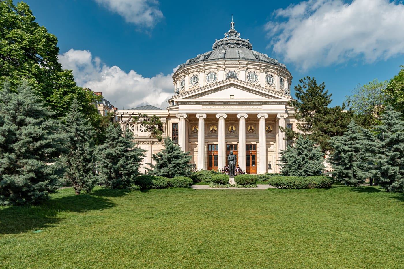 The Romanian Athenaeum's columned facade framed by trees in central Bucharest